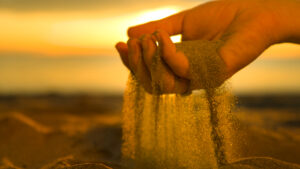 Hand full of sand falling through fingers
