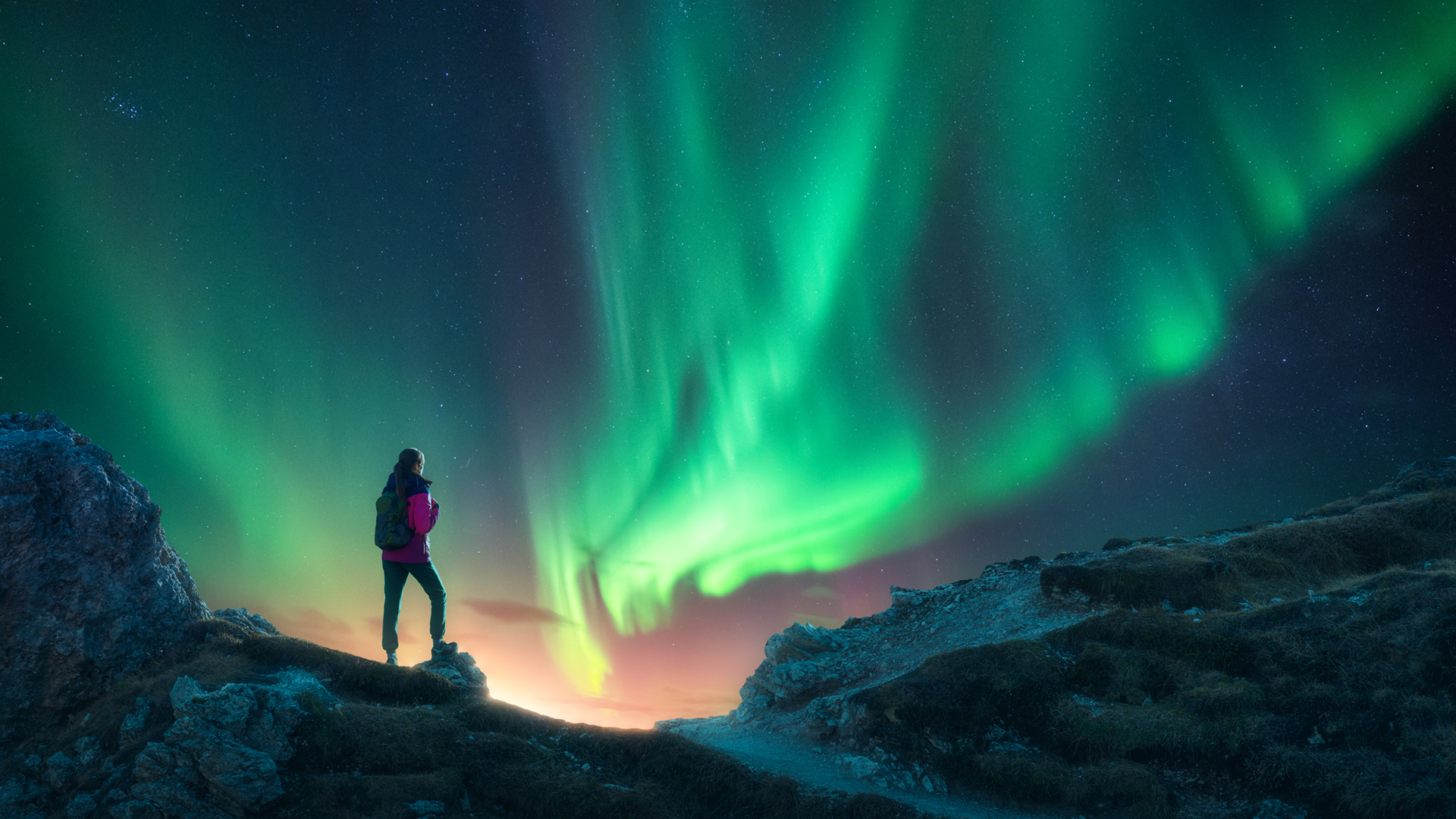 Northern lights and young woman on mountain peak at night. Aurora borealis and silhouette of alone girl on mountain trail.